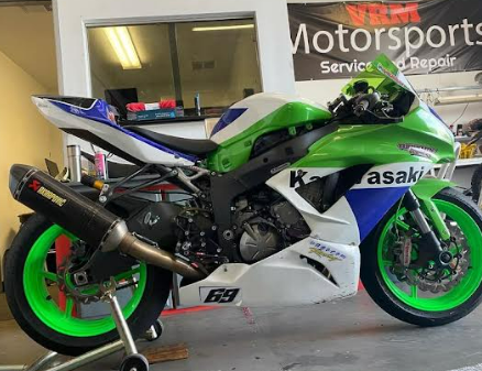 Green and white Kawasaki sport motorcycle parked in a garage, side view with neon green rims.