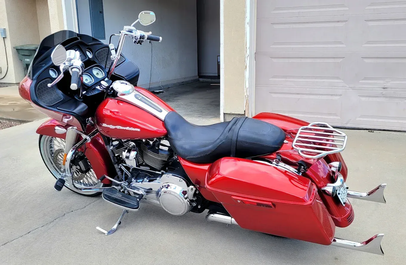 Red touring motorcycle parked in a driveway, with saddlebags and a windshield.