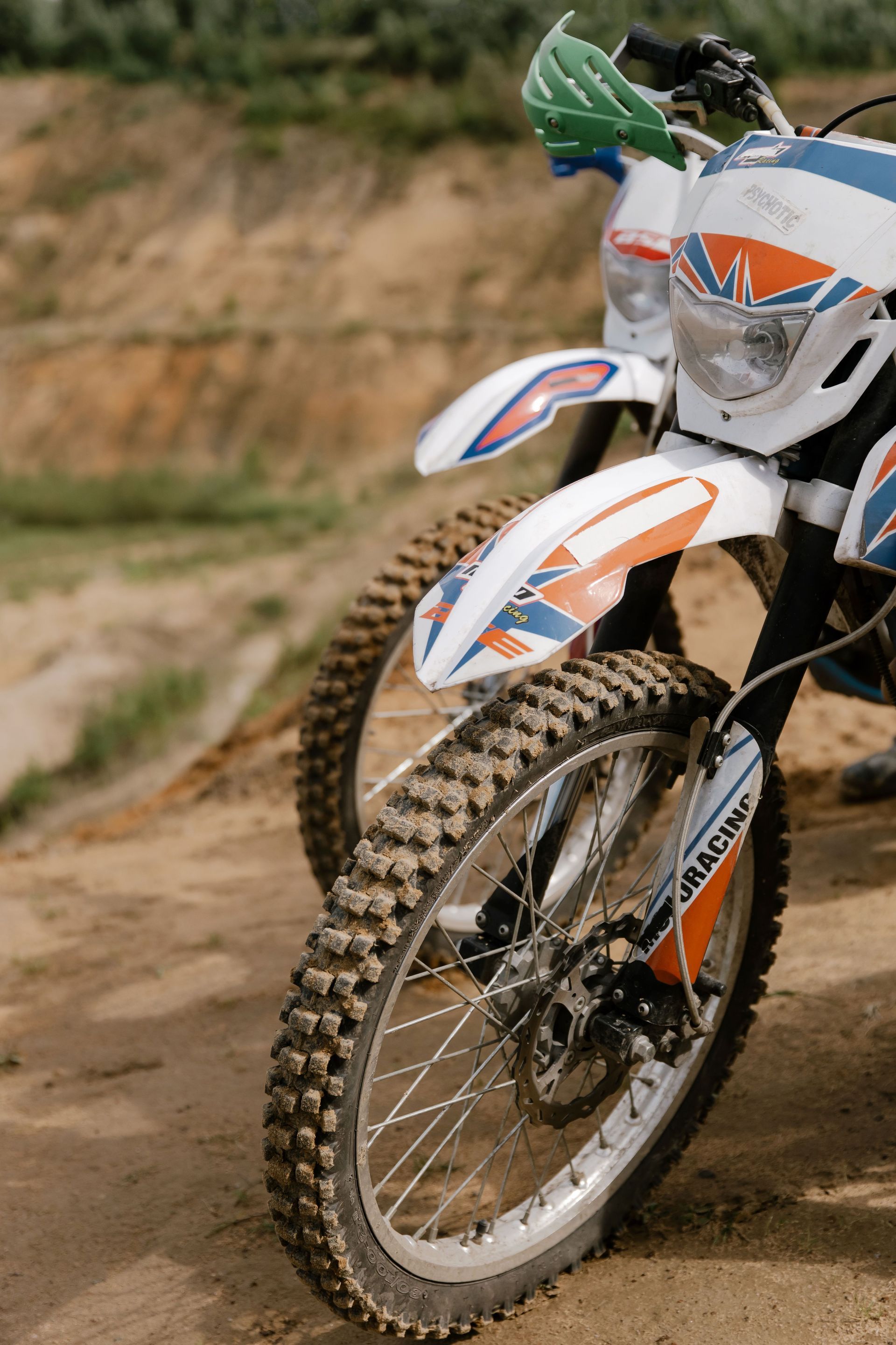Motocross rider on a white-orange dirt bike speeding on a sandy track