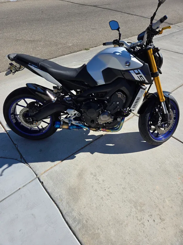 Black and blue sport motorcycle parked on a concrete driveway in bright sunlight