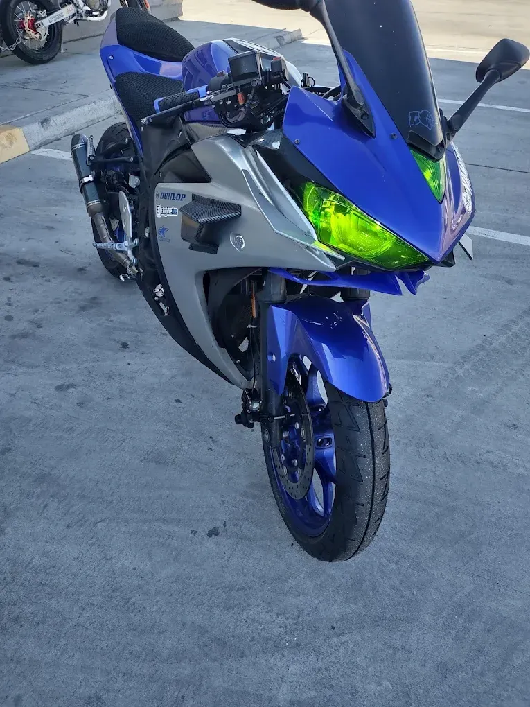 Blue and gray sport motorcycle with neon green headlights parked on pavement